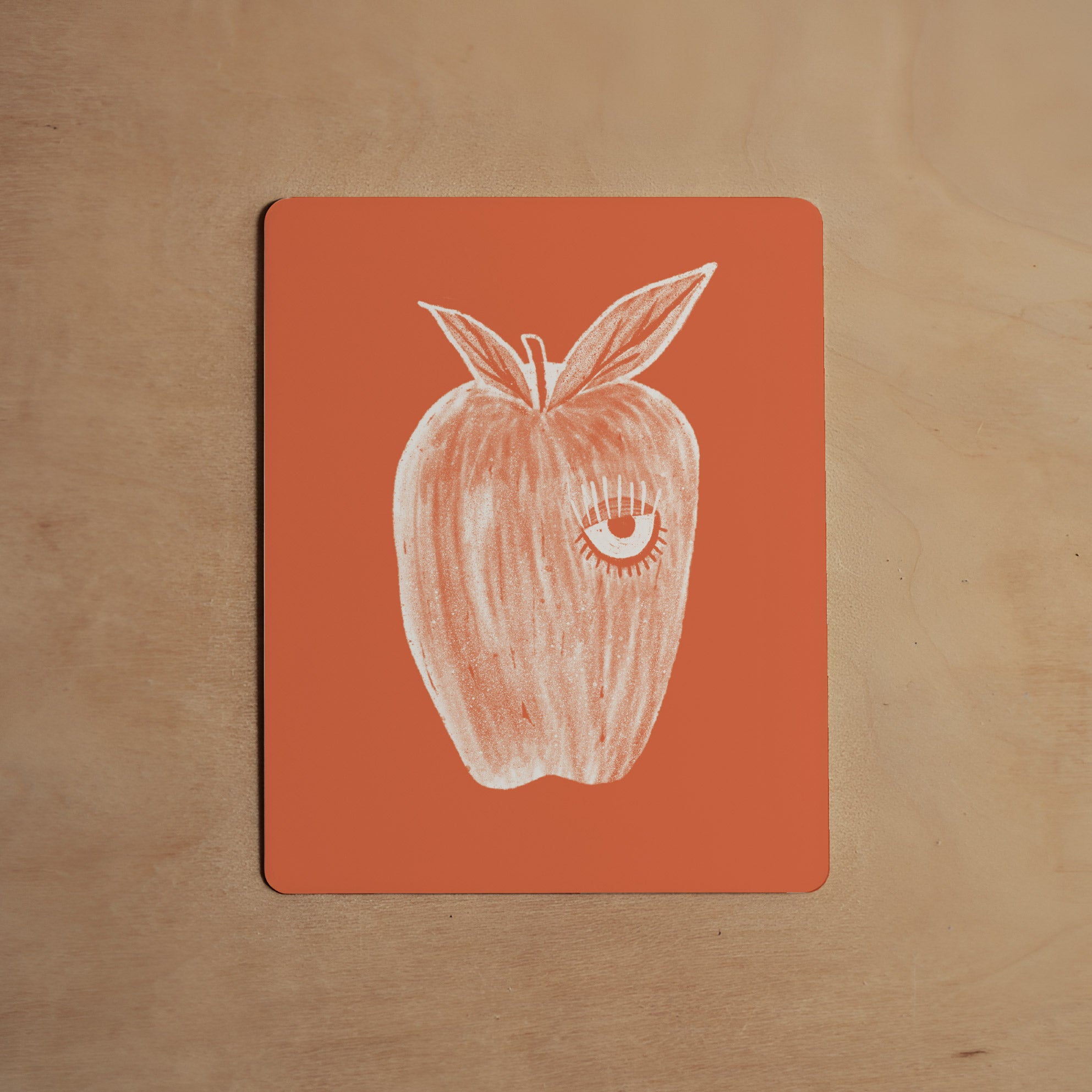 Card with a white apple illustration on an orange background, placed on a wooden surface.