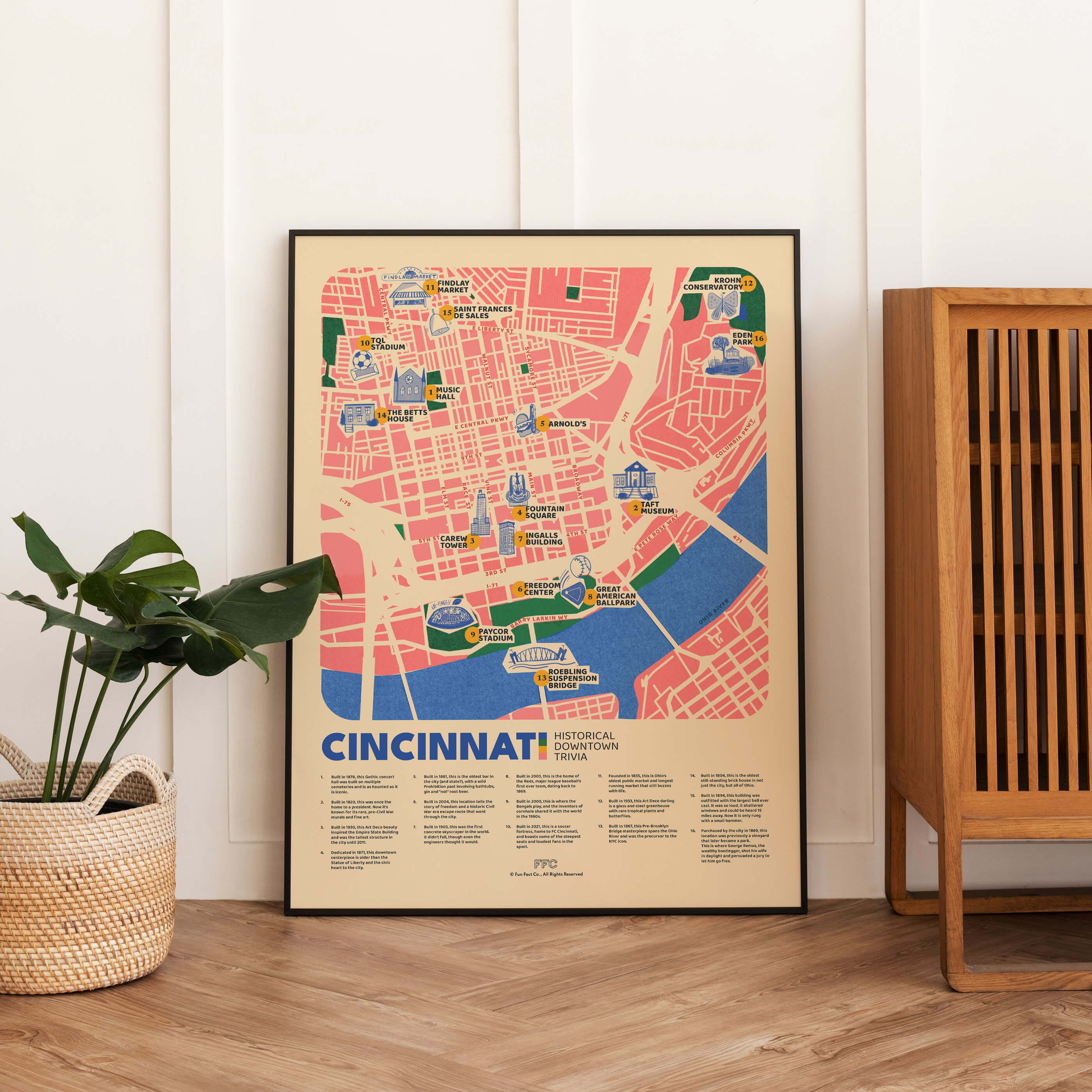 Framed map of Cincinnati on a wall next to a plant and wooden cabinet