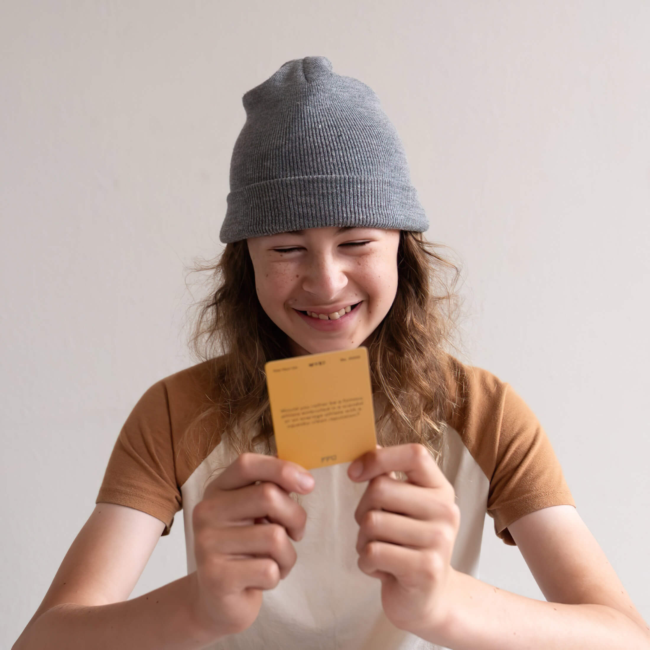 person wearing a beanie playing a would you rather card game and smiling