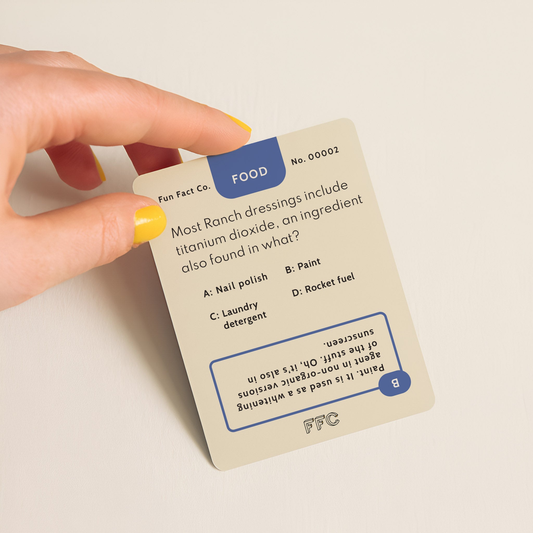 Hand holding a trivia card with a question about ranch dressings and titanium dioxide.